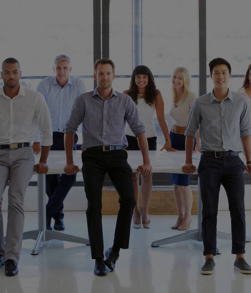 A diverse group of business professionals posing confidently in an office.