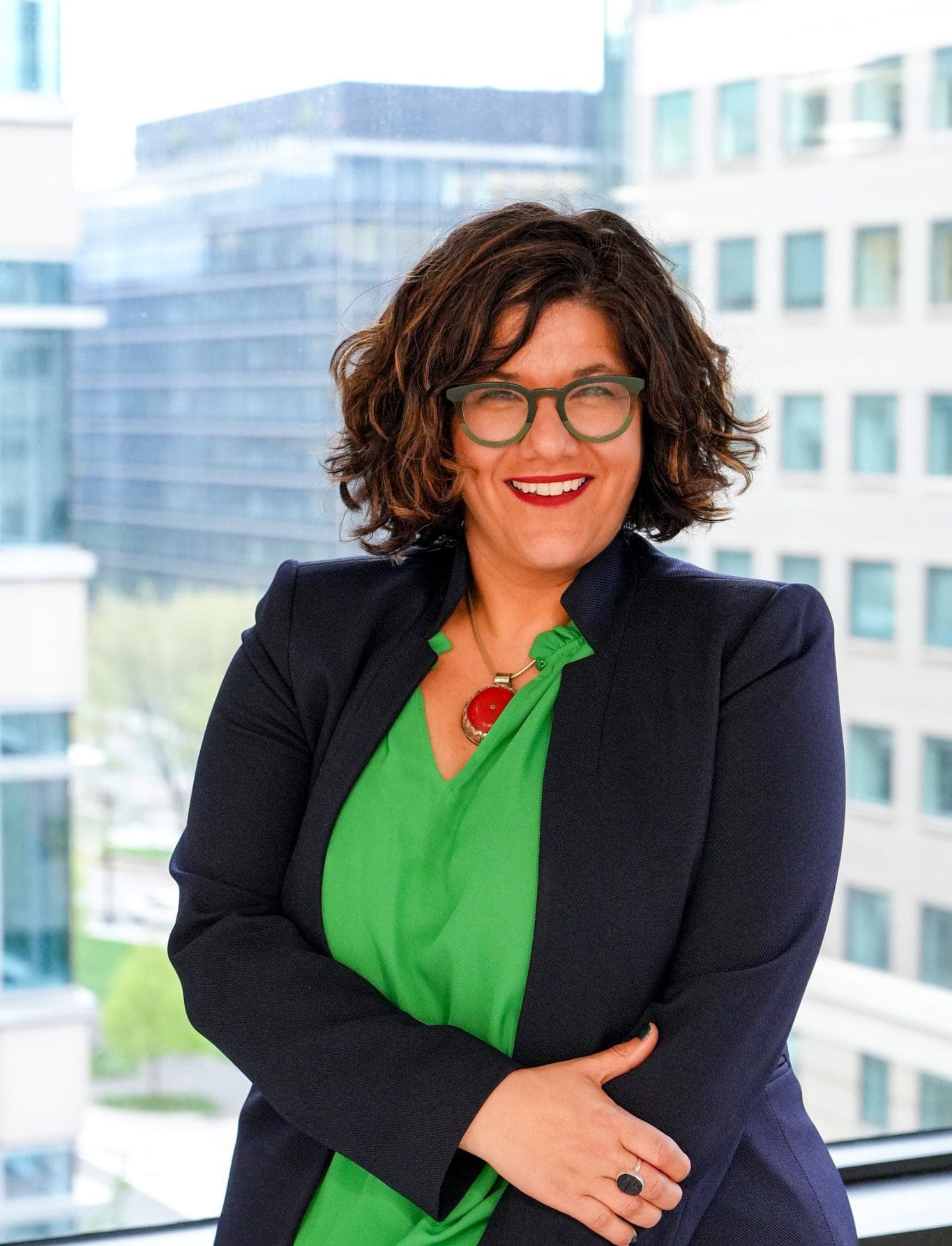 Confident woman in business attire smiling with arms crossed.